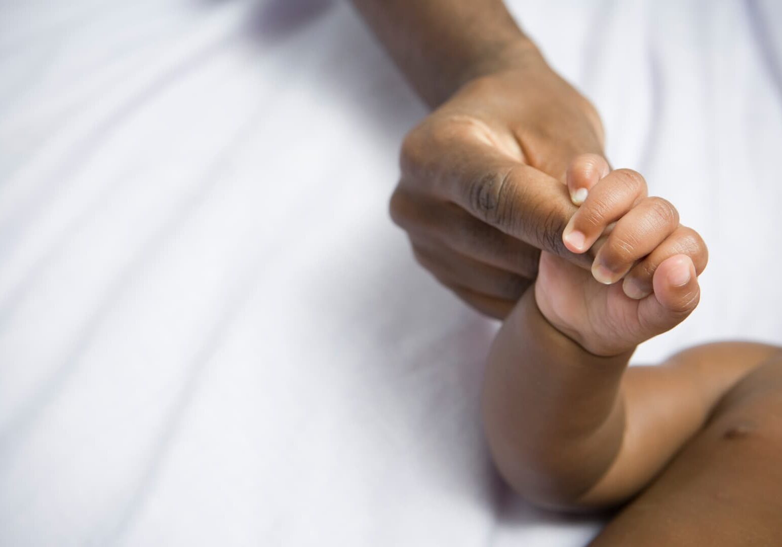 parent's hands holding baby's hand